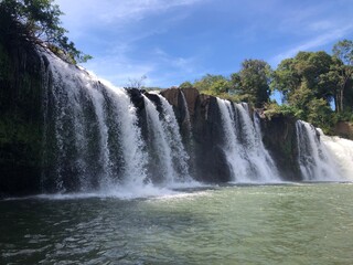 Fototapeta premium Scenic waterfall cascading into a serene pool surrounded by lush greenery.