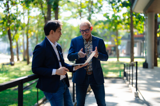 Businessmen discussing new ideas outside using laptop