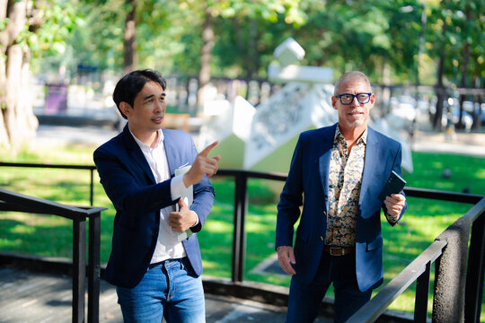 Business partners discussing strategy outdoors pointing direction