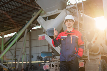 A cheerful Asian construction worker stands in front of a large pile of concrete blocks. He holds one block and gives a confident thumbs up. Quality control, acceptance at construction site.