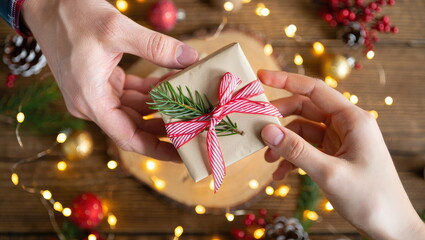 Hands exchanging a beautifully wrapped gift surrounded by festive decorations during the holiday season