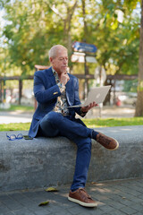 Obraz premium Senior man thinking while using laptop outdoors