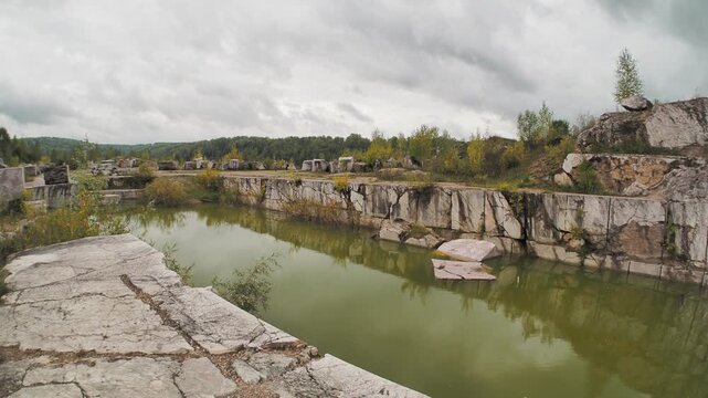 Minerals. People are walking through an old marble quarry next to a pond that was formed where marble blocks were removed. Hand held. Siberia.