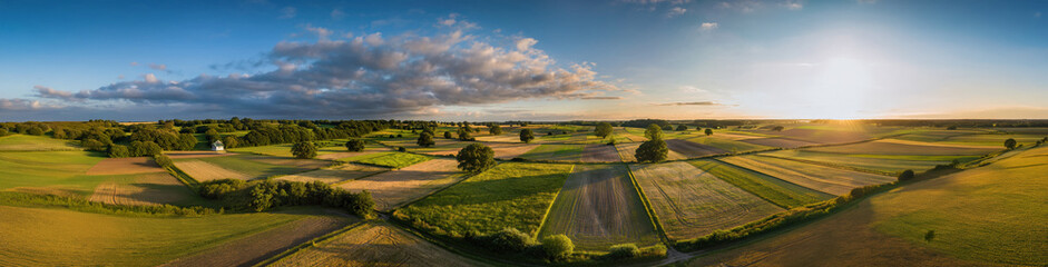 Fototapeta premium 4K Ultrawide Panoramic Nature Landscapes Backgrounds - Panoramic view of cultivated fields and meadows under a dramatic sky