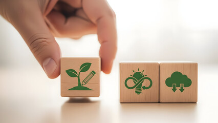 Hand placing wooden block with plant sprout symbol next to recycling and tree icons