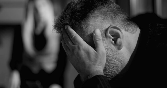 Male employee under intense pressure with head in hand while female boss yells in background, symbolizing emotional strain and accountability in high-stakes office setting