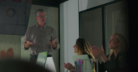 Fototapeta premium Male presenter smiling and encouraging applause with motivational energy after successful presentation during office team meeting in modern conference room