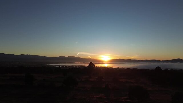 Golden sunrise above foggy lake and silhouettes of mountains in Mexico pan left and zoom out camera movement