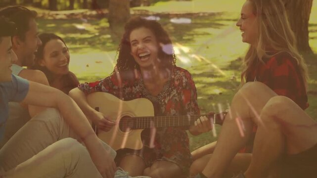 Central woman picking up guitar and strumming, friends leaning in to listen, light leaks overlaying