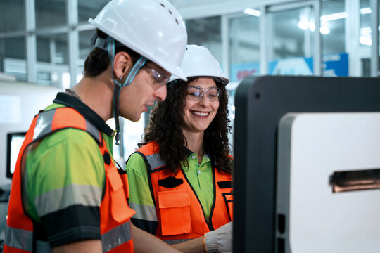 Two people wearing safety gear are looking at a computer screen - Powered by Adobe