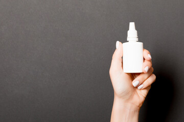 Female hands hold medicine bottle nose spray on Black background isolation