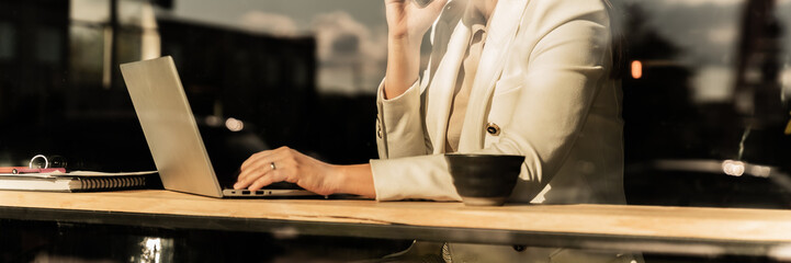 Professional Woman Working On Laptop In Café During Golden Hour Light With Coffee On Table