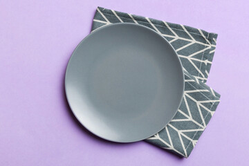 Top view on colored background empty round gray plate on tablecloth for food. Empty dish on napkin with space for your design