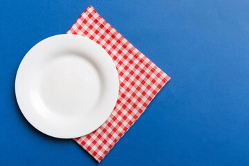 Top view on colored background empty round white plate on tablecloth for food. Empty dish on napkin with space for your design