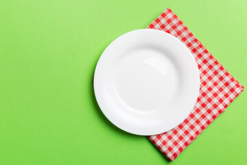 Top view on colored background empty round white plate on tablecloth for food. Empty dish on napkin with space for your design