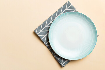Top view on colored background empty round blue plate on tablecloth for food. Empty dish on napkin with space for your design