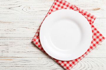 Top view on colored background empty round white plate on tablecloth for food. Empty dish on napkin with space for your design
