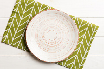 Top view on colored background empty round white plate on tablecloth for food. Empty dish on napkin with space for your design