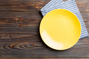 Top view on colored background empty round yellow plate on tablecloth for food. Empty dish on napkin with space for your design