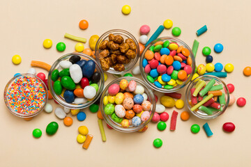 different colored round candy in bowl and jars. Top view of large variety sweets and candies with copy space