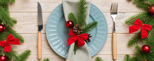 Christmas table place setting with christmas decor and plates, kine, fork and spoon. Christmas holiday background. Top view