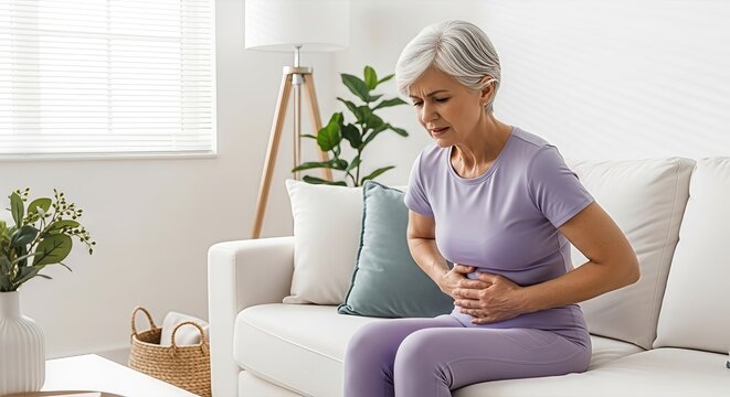 Mature woman experiencing abdominal pain or digestive discomfort while sitting at home