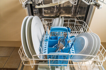 Plates, dishes and cutlery in the dishwasher, viewed from in front of appliance