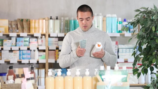 Male buyer chooses skin cream at the drugstore. High quality 4k footage