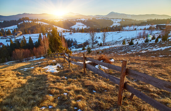 Rustic wooden fence on a mountain meadow with snowy peaks in the background.