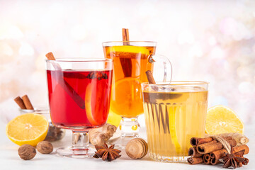Three different Hot Toddy drinks in different tea cups - hot autumn winter tea cocktail beverages with scotch, rum and mezcal alcohol drinks, spices, lemon and honey