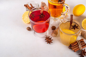 Three different Hot Toddy drinks in different tea cups - hot autumn winter tea cocktail beverages with scotch, rum and mezcal alcohol drinks, spices, lemon and honey