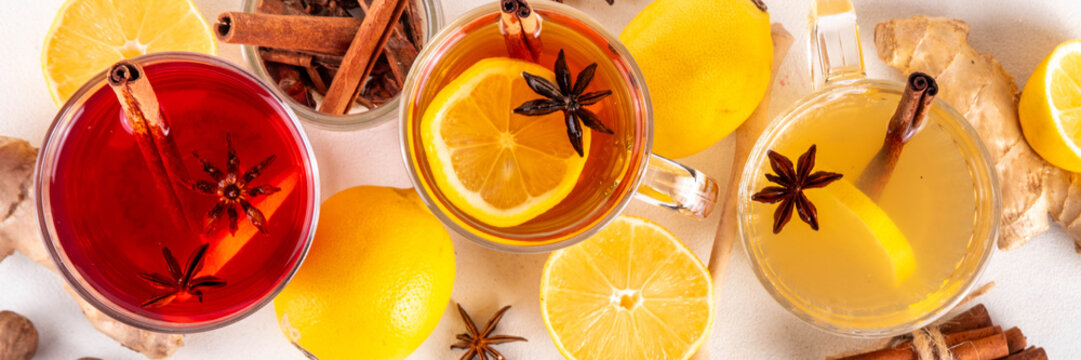 Three different Hot Toddy drinks in different tea cups - hot autumn winter tea cocktail beverages with scotch, rum and mezcal alcohol drinks, spices, lemon and honey - Powered by Adobe