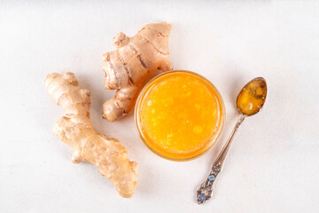 Homemade caramelized ginger jam marmalade preserves in small jar with fresh ginger roots on white...