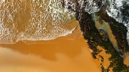 Aerial View of Waves Hitting a Stone Rock Stripe at Santa Cruz Beach Portugal