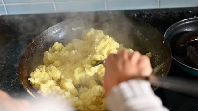 Woman cooking traditional Granada-style flour migas in a rustic pan for a family meal