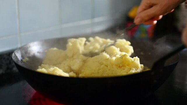 Hands stirring Granada-style flour migas in a rustic pan with a traditional metal rasera