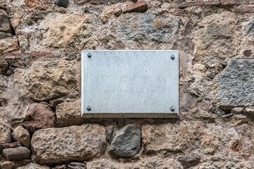 Blank marble plaque mockup mounted with steel bolts on an ancient textured stone wall. Empty plaque...
