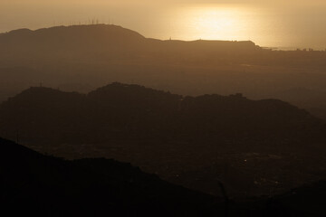 Hillside shantytown contrasting with a distant modern city skyline in the mist, illustrating social inequality, poverty, and urban sprawl in Lima, Peru