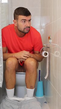 Embarrased looking man caught by someone on the toilet 