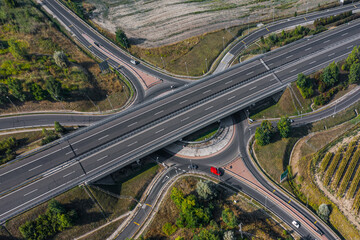 Fototapeta premium Daytime aerial view of a highway overpass and roundabout connection. Clean lines, modern infrastructure and smooth traffic routes.