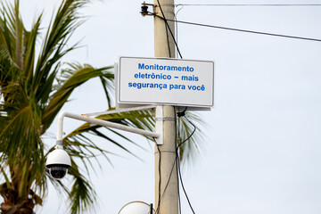 Poste com c&acirc;mera de vigil&acirc;ncia e placa informando o monitoramento para a seguran&ccedil;a dos cidad&atilde;os. 