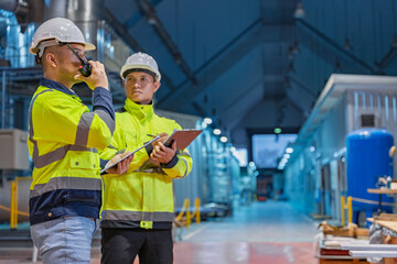 Engineers inspecting machinery and workers organizing inventory on shelves inside a busy warehouse,...