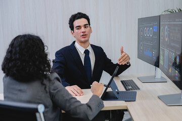 Business professionals analyzing data and discussing financial reports with digital dashboards and graphs in a modern office setting, focusing on strategy and performance.