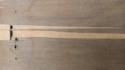 Damaged Plywood Texture With Torn Strip. A weathered plywood surface featuring a torn horizontal strip, splintered edges, and dark cracks revealing inner layers