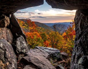 Cave opening overlooking a valley filled with autumn foliage under a colorful, late-day sky