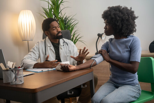 Doctor measuring blood pressure to a smiling woman.