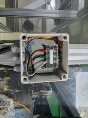 Electrical junction box with multiple colored wires connected to terminals, showcasing intricate wiring and components in a modern industrial setting