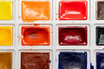Close-up of a palette with multi-colored paints in a box, new but already used, open paints for creativity