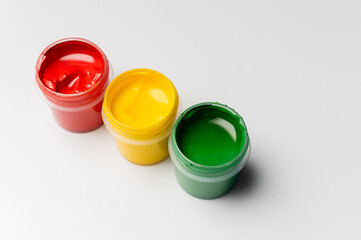 Artist's gouache, top view from the side. Three open bottles of gouache for painting on a pure white background. New paints for painting