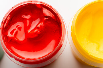jar of bright red paint, macro shot of the texture. Paint on a white table, a drawing and art tool